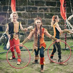 drei mittelalterliche Gaukler jonglieren Keulen und drehen Reifen