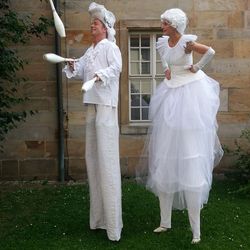 Zwei Stelzenläufer in weißen Barock-Kostümen